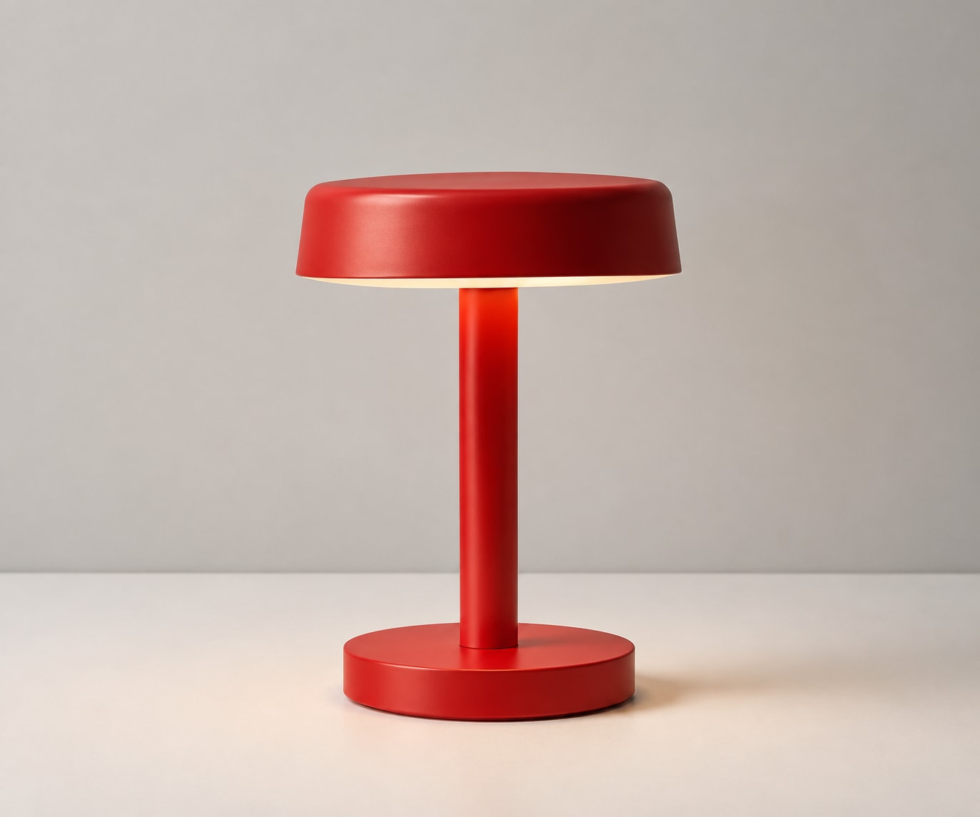 Scarlet-red metal table lamp with a round shade and circular base